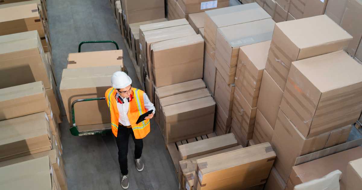 Logistic warehouse worker delivering boxes on a trolley | Differences Between Warehousing and Logistics Services