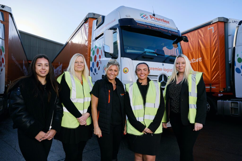 Five women in high vis jackets standing in front of Premier Logistics trucks in Leicester